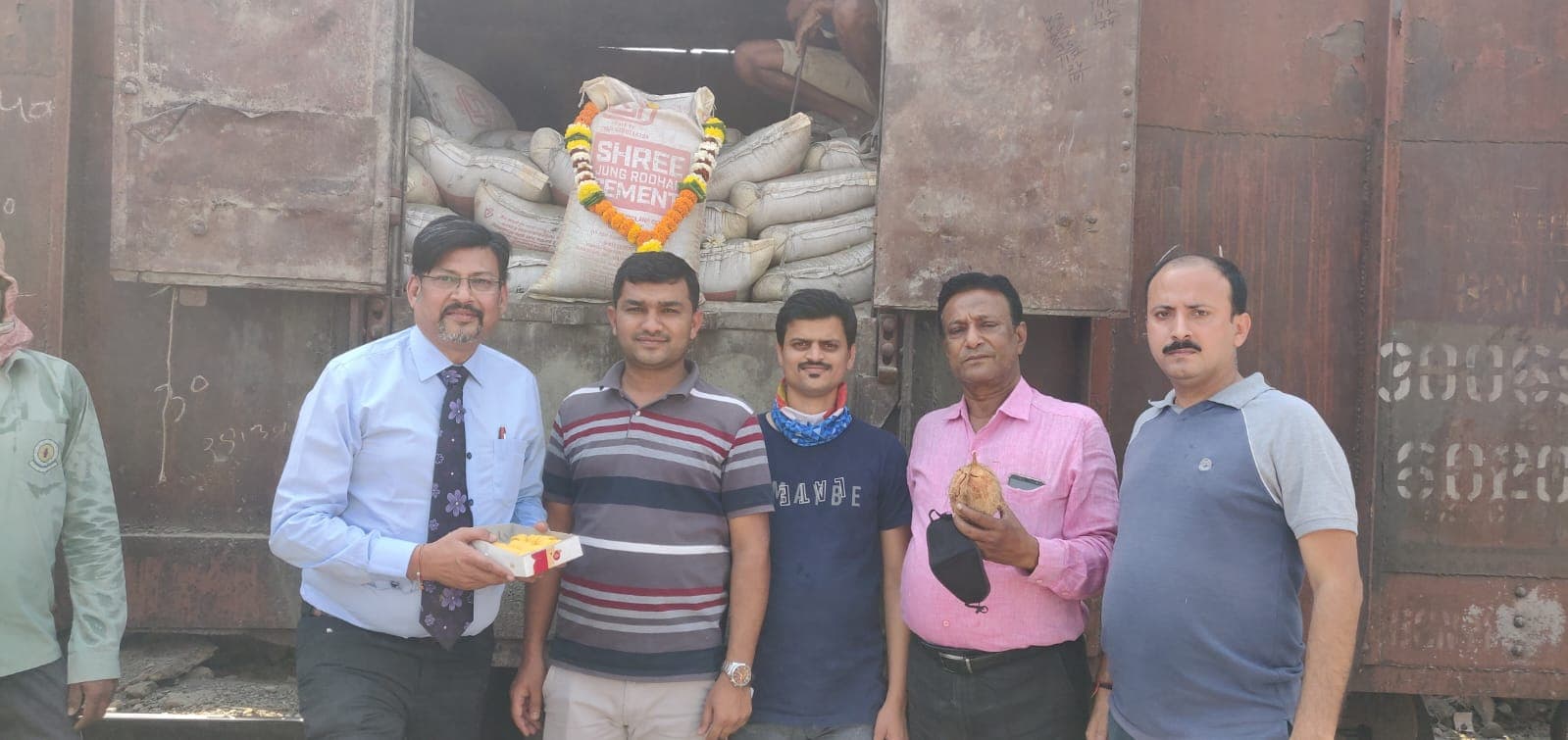 Ashay Shah and the team celebrating a cement wagon dispatch with a ceremonial garland