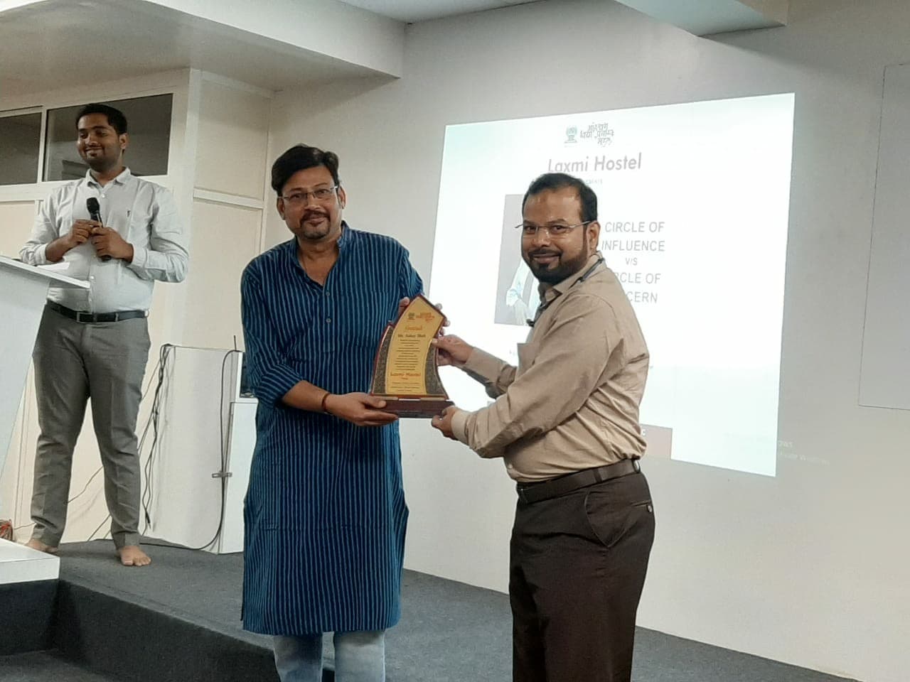 Ashay Shah receiving a recognition award on stage at Laxmi Hostel